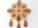 a gold and amethorate broochle with purple stones