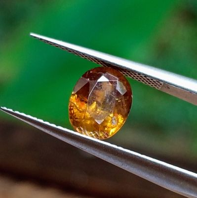 un gros plan d'un diamant jaune tenu par une paire de pinces