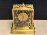 a gold clock sitting on a table with a black background