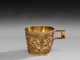 a gold cup with a design of birds and flowers on it
