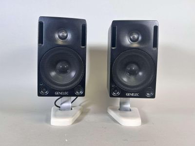 two speakers are sitting on a white stand on a white surface