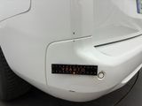 the rear end of a white car with a sticker on it ' s bumper