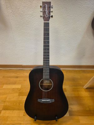 an acoustic guitar sitting on top of a hard wood floor