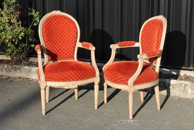 pair of orange velvet upholstered chairs in front of a black wall