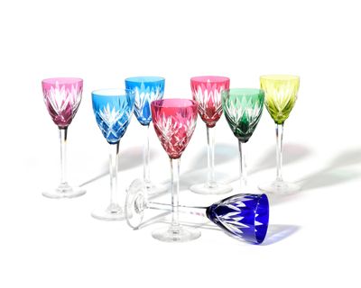Des verres à vin aux couleurs vives sont alignés en rangée sur une surface blanche