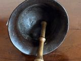 a metal bowl with a wooden handle on a wooden table