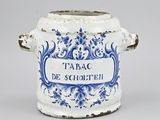 an old blue and white pot with a handle and a sign on it