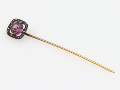 un gros plan sur une pierre violette et une épingle en or
