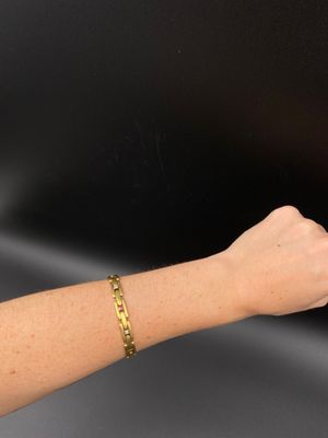 a woman ' s arm with a gold bracelet on it