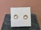 un gros plan sur une paire de boucles d'oreilles en or posées sur un bloc de marbre