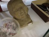 une statue représentant un homme assis sur une table, à côté d'une boîte de bonbons