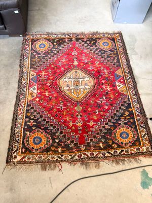 un tapis oriental posé à même le sol dans une pièce où se trouve une chaise