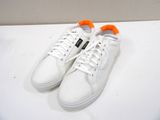 white sneakers with orange laces on top of a white surface