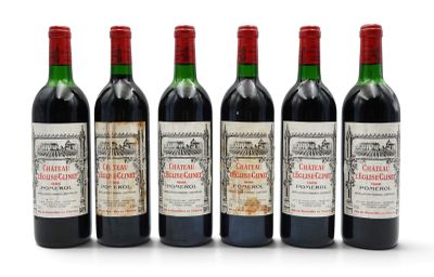 six bottles of wine are lined up in a row on a white surface
