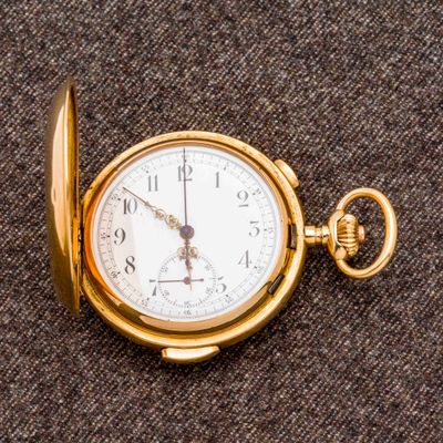 une montre de poche en or posée sur un tissu marron