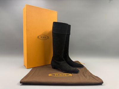 une paire de bottes noires posée sur un tissu marron