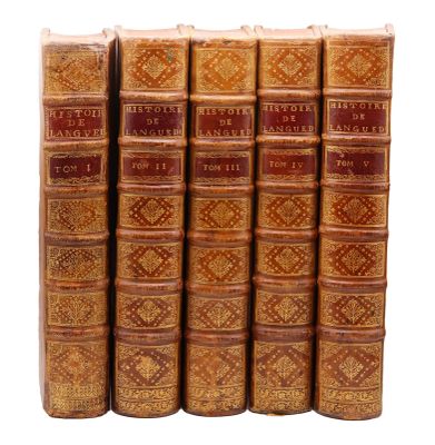 six vieux livres sont alignés sur une surface blanche