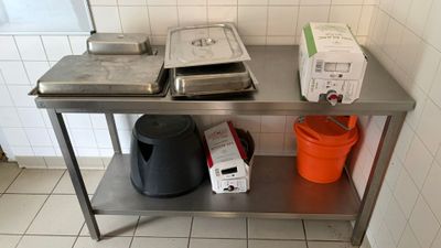 a metal table with two pans and a trash can on it