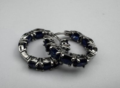 une paire de boucles d'oreilles créoles argentées ornées de pierres bleues