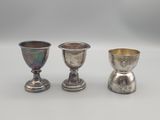 trois gobelets en argent posés les uns à côté des autres sur une table