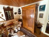 un salon avec un canapé, un fauteuil, un miroir et une armoire