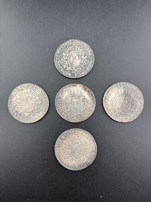 quatre pièces d'argent empilées les unes sur les autres sur une surface noire