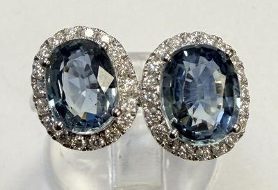 une paire de boucles d'oreilles en saphir bleu et diamants posées sur une surface transparente