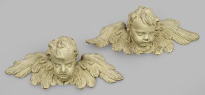 une paire de têtes d'anges sculptées sur fond gris