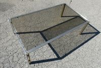 Table basse piètement métallique et plateau de verre fumé.