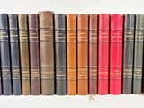 several old books are lined up in a row on a white surface
