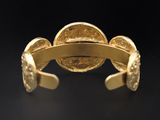 a close up of a gold cuff with a coin on it