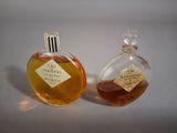 two bottles of perfume sitting next to each other on a table