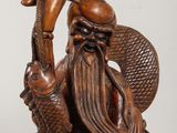 an image of a wooden statue of a man with a fish