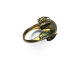 un gros plan d'une bague en or ornée d'une feuille verte
