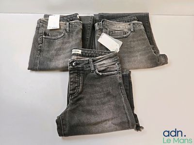 trois paires de jeans gris posées sur une table blanche