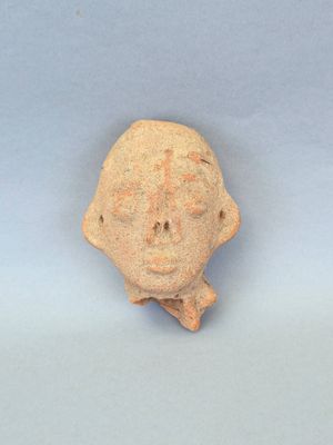 une petite tête d'homme en argile sur laquelle est gravée une croix