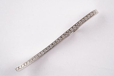 un gros plan d'une broche en forme de barre sertie de diamants posée sur une surface blanche