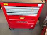 une boîte à outils rouge à roulettes et à tiroirs dans un garage