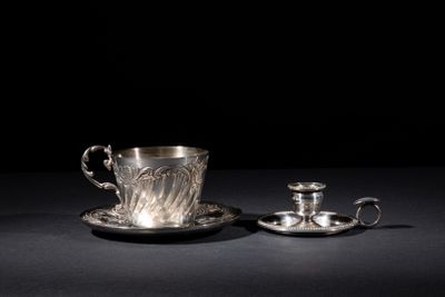 a silver cup and saucer with a saucer on a black surface
