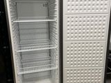un réfrigérateur vide, la porte ouverte, dans une pièce