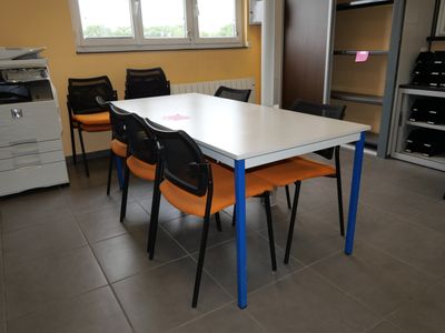 a white table with orange chairs and a black printer