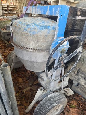 une bétonnière posée à côté d'un tas de ferraille