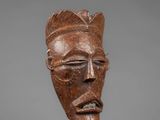 a close up of a wooden mask on a metal stand