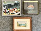 Deux tableaux encadrés représentant des bateaux et une corbeille de fruits sont posés sur un tapis