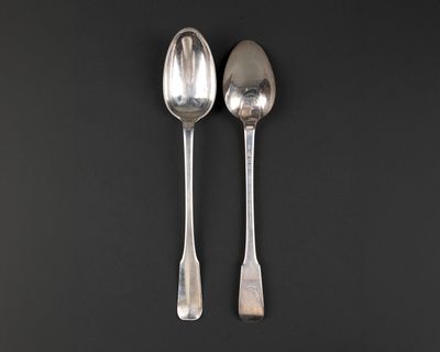 two silver spoons on a black surface with a black background