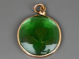 un gros plan d'un pendentif en verre vert contenant une feuille