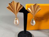 pair of gold tone earrings with pearls on a black stand