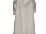 une robe de mariée suspendue à un cintre sur un mur blanc