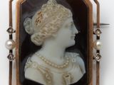un camée ancien représentant une femme avec des perles dans les cheveux