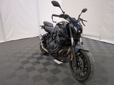 une photo d'une moto noire garée sur un sol à damier